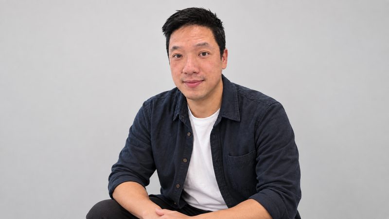 David Lau, seated, wearing a dark shirt over a white t-shirt